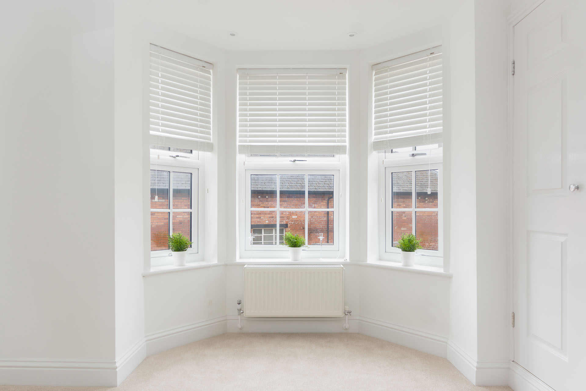 How to Choose the Perfect Blinds for Bay Windows - this image shows faux wooden venetian blinds fitted into a bay window