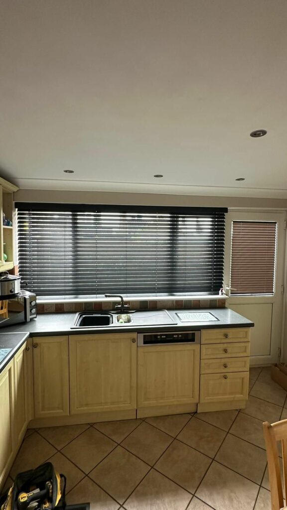 Black Venetian blinds fitted in a modern Northampton kitchen, providing stylish light control, privacy and a contemporary finish across the large window space.