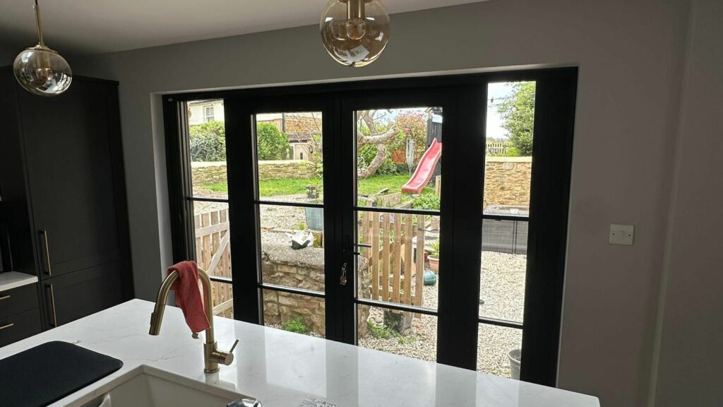 Black blind screen system fitted across large glazed doors in a modern Market Harborough kitchen, providing contemporary shading, privacy and a sleek minimalist appearance.