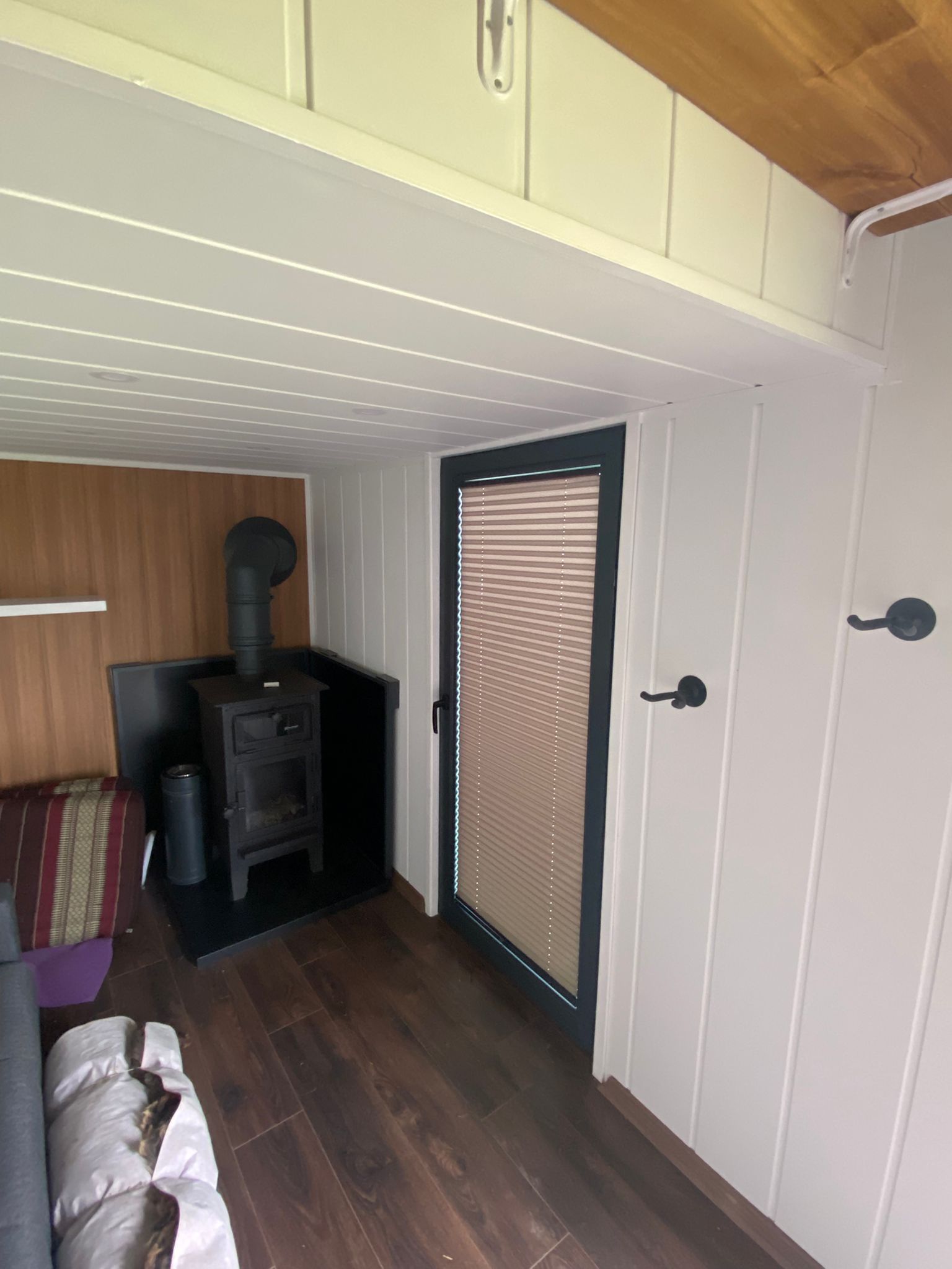 Pleated blind fitted beside wood-burning stove in trailer conversion