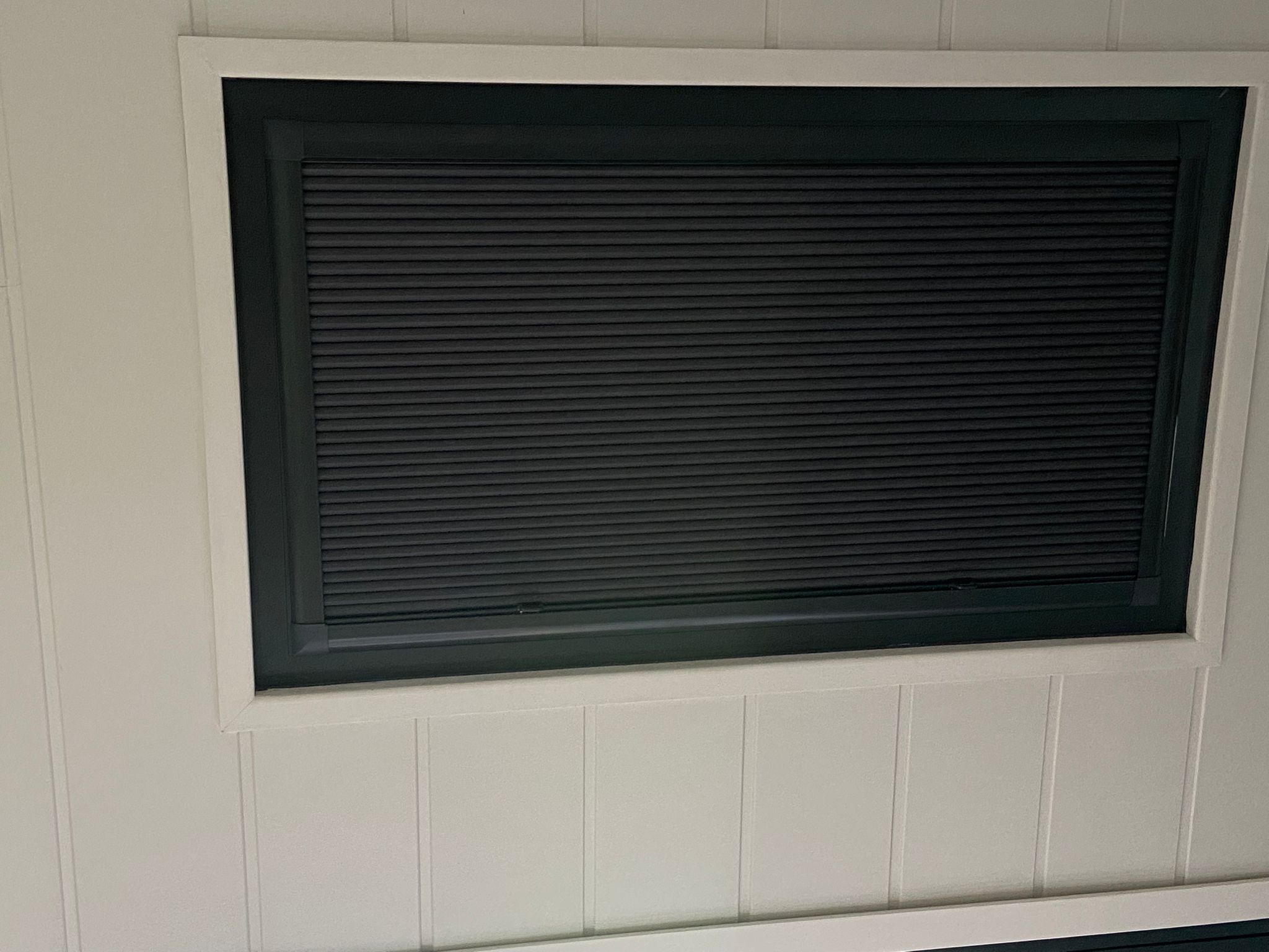 Closed pleated blind fitted neatly within dark trailer window frame